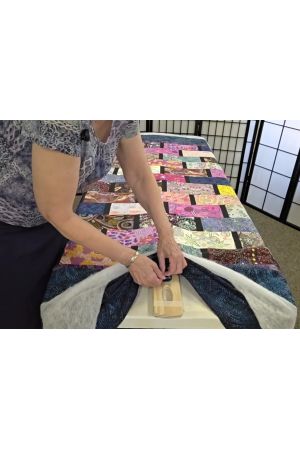 securly pins quilt to basting bar